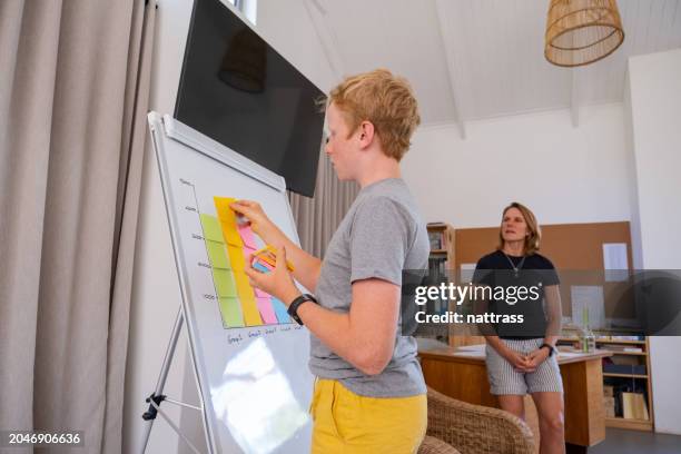 il ragazzo della scuola usa i post-it per vedere quale gruppo classe vince - segnalibro foto e immagini stock