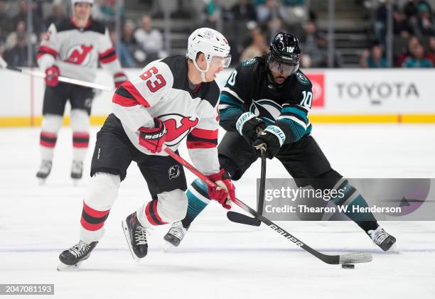 Jesper Bratt of the New Jersey Devils skating with the puck is defended by Anthony Duclair of the San Jose Sharks during the first period of an NHL...