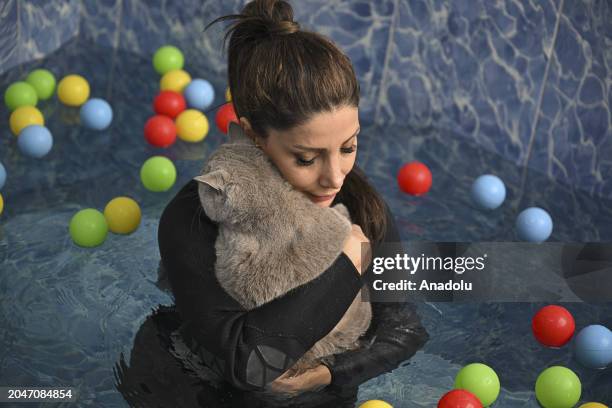 Physiotherapist Yagmur Denli holds 4-year-old cat, Siraz, who tries to get rid of its excess weight by doing pilates and swimming in the pool as it...