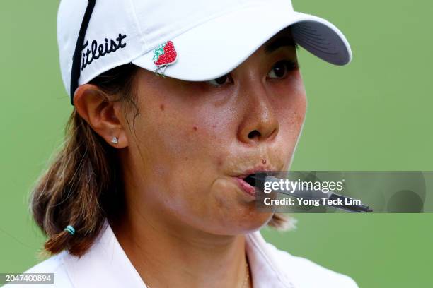 Danielle Kang of the United States bites on a sharpie as she walks off the 18th green after finishing play during Day One of the HSBC Women's World...