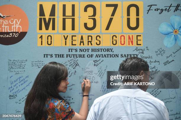 Woman writes a message during an event held by relatives of the passengers and supporters to mark the 10th year since the Malaysia Airlines flight...