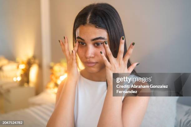 woman applying cream for dark circles under her eyes - sérum visage photos et images de collection