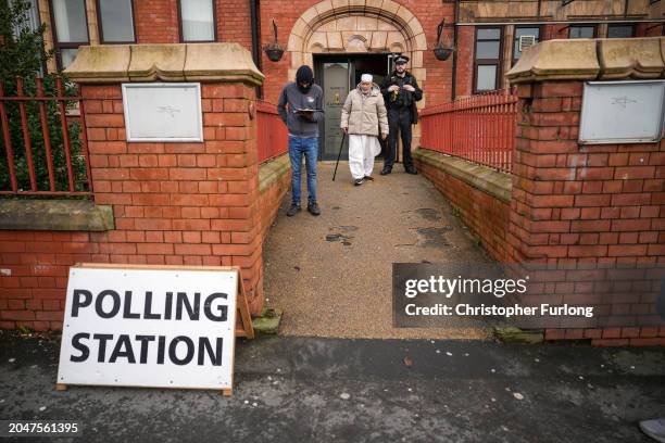 Voter leaves a polling station, guarded by a police officer, after voting in the Rochdale by-election on February 29, 2024 in Rochdale, England. The...