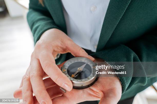 businesswoman holding compass in hand at office - kompass stock-fotos und bilder
