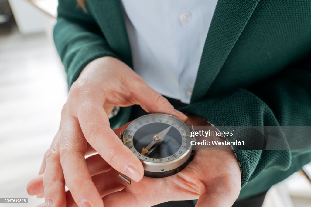 Businesswoman holding compass in hand at office