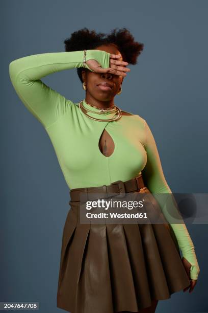 woman wearing green top with brown leather skirt and covering eyes - metallic skirt foto e immagini stock