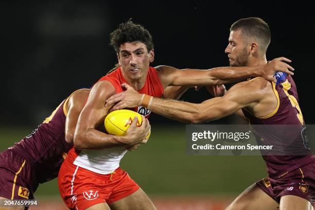 Justin McInerney of the Swans is tackled by James Tunstill of the Lions and Josh Dunkley of the Lions during the 2024 AFL Community Series match...