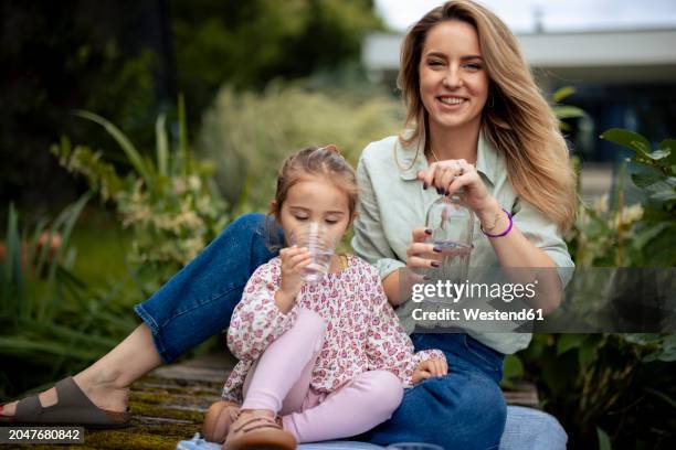 smiling mother with daughter drinking water on pier - niño-tomando-agua fotografías e imágenes de stock