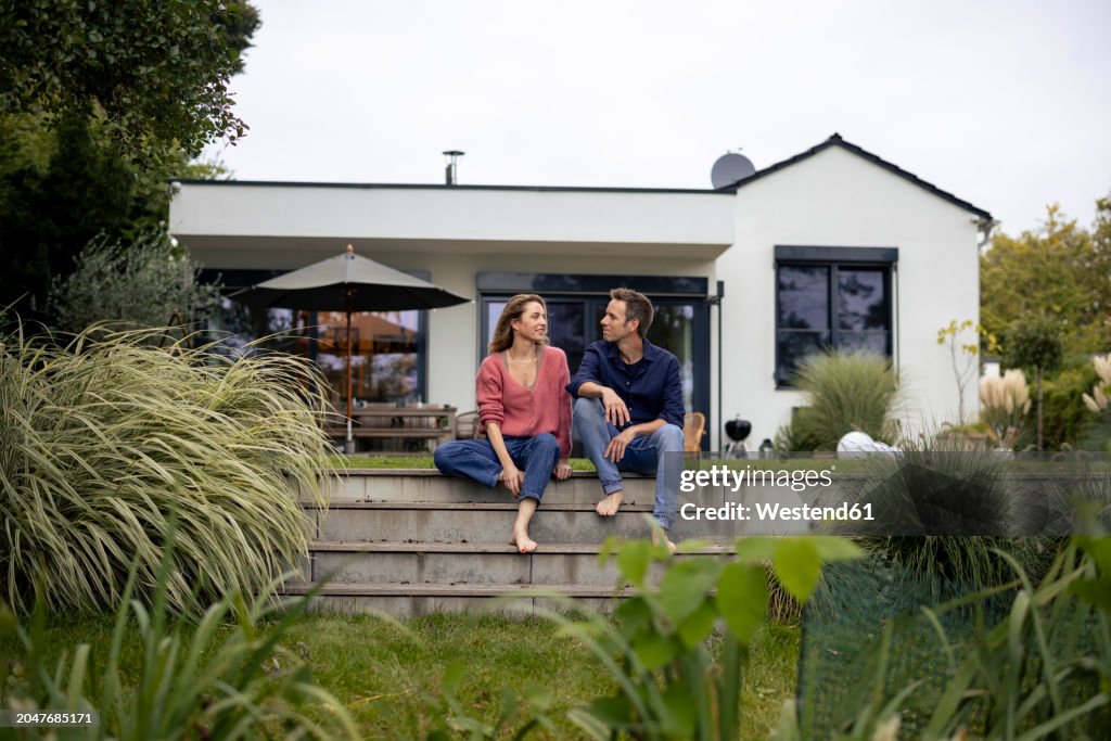 Smiling couple looking at each other in front of house