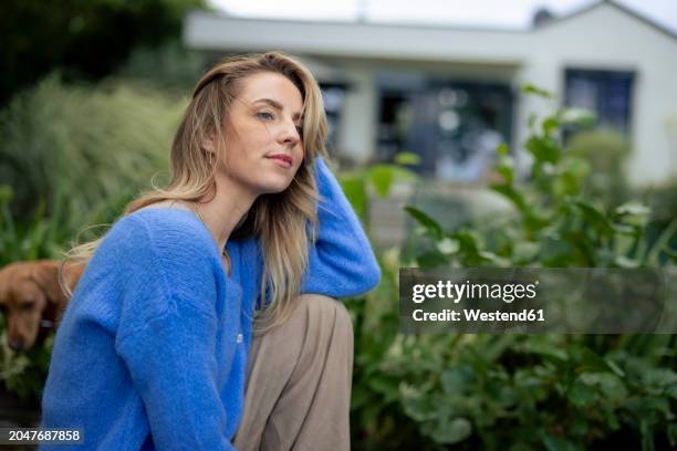 thoughtful woman sitting near plants in garden - cadrage aux genoux photos et images de collection