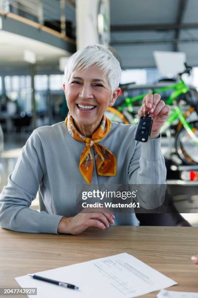 happy senior woman holding car keys at desk - mid adult stock pictures, royalty-free photos & images