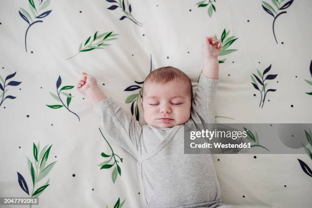 cute baby girl stretching arms lying in bed at home - sólo bebés fotografías e imágenes de stock
