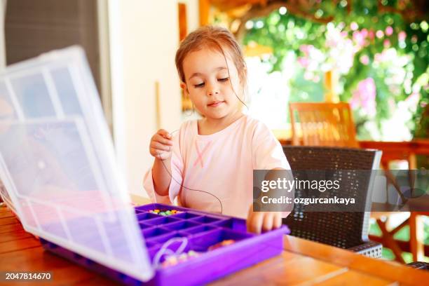 little girl making beaded jewelry at table, closeup - wooden bead stock pictures, royalty-free photos & images