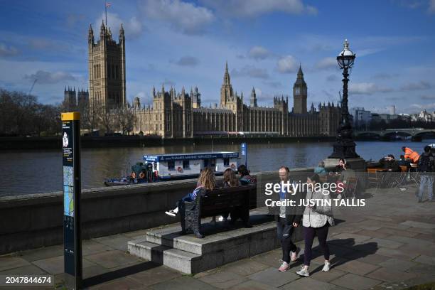 Members of the public walk along the South Bank in the early spring sunshine beside the River Thames, with the Palace of Westminster, home to the...