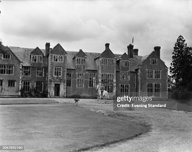 Man poses on horseback in front of Loseley Park, a Tudor manor house near Guildford in Surrey, September 7th 1953. Loseley Park is owned by the...