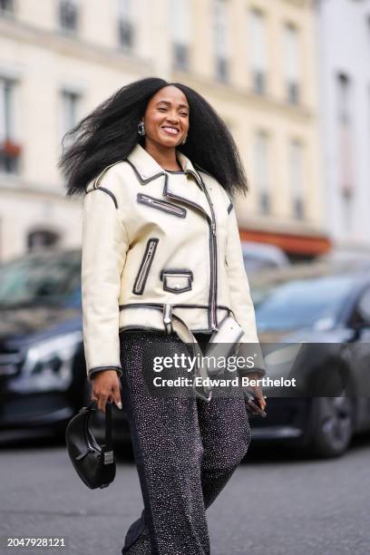 Guest wears a white leather jacket , flared pants with shiny glitter details , outside Undercover, during the Womenswear Fall/Winter 2024/2025 as...
