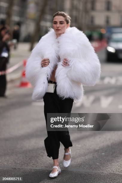 Fashion Week Guest was seen wearing white miumiu ballerinas, a long black skirt, a bra out of jewelry, a white feather jacket, a white chanel bag...