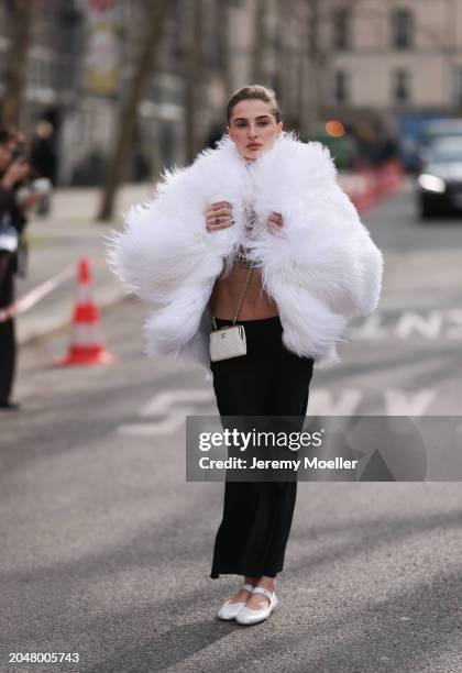 Fashion Week Guest was seen wearing white miumiu ballerinas, a long black skirt, a bra out of jewelry, a white feather jacket, a white chanel bag...