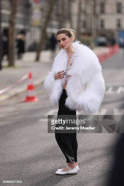 Fashion Week Guest was seen wearing white miumiu ballerinas, a long black skirt, a bra out of jewelry, a white feather jacket, a white chanel bag...