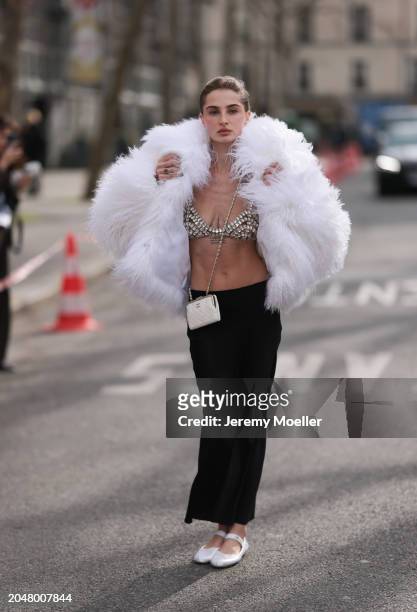 Fashion Week Guest was seen wearing white miumiu ballerinas, a long black skirt, a bra out of jewelry, a white feather jacket, a white chanel bag...