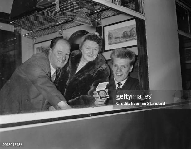 Scottish boxer Dick McTaggart with his parents on a train showing his Melbourne Olympics Lightweight boxing gold medal, December 14th 1956.
