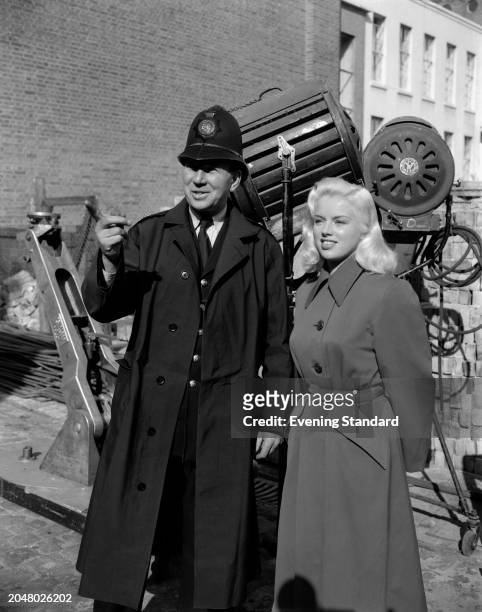 Actress Diana Dors on set during a break in the filming of 'Yield to the Night' alongside a policeman, October 21st 1955.