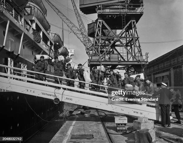 British Army soldiers carry their kit on a gangplank aboard a Royal Navy troop ship during the Suez Crisis, Southampton Docks, August 20th 1956. The...