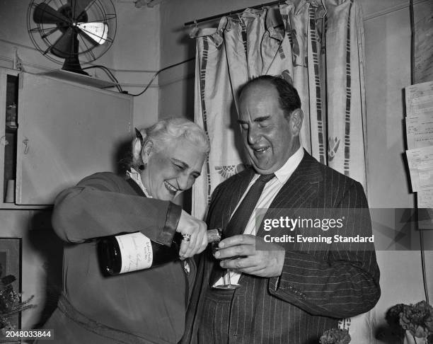 Actress Violet Farebrother pours a glass of wine for actor Robert Morley , August 27th 1956.