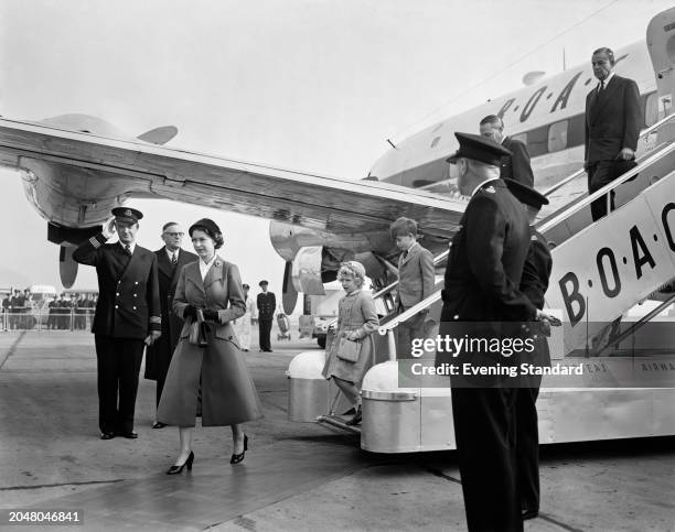 Queen Elizabeth II with Princess Anne and Prince Charles descending aircraft steps behind her after saying goodbye to Prince Philip aboard a plane at...