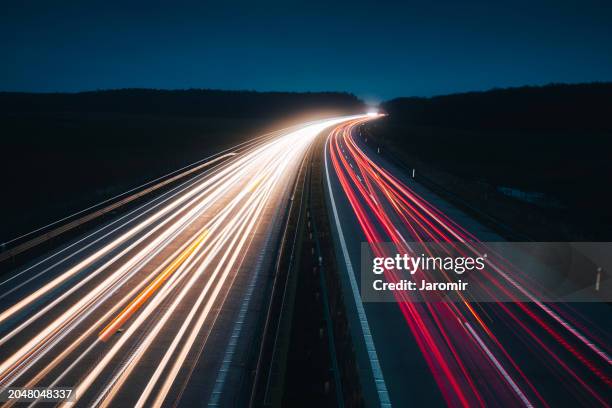 light trails on highway at night - geschwindigkeit stock-fotos und bilder
