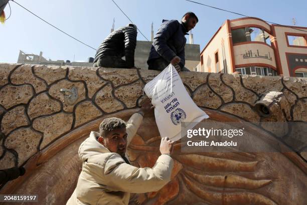 Palestinians flock to receive flour distributed by The United Nations Relief and Works Agency for Palestinian Refugees in the Near East in Gaza,...