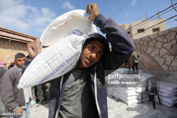 Palestinians flock to receive flour distributed by The United Nations Relief and Works Agency for Palestinian Refugees in the Near East in Gaza,...