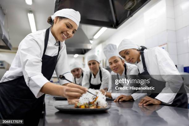 glückliche studentin dekoriert einen teller in einem kochkurs - gastronomiebetrieb stock-fotos und bilder