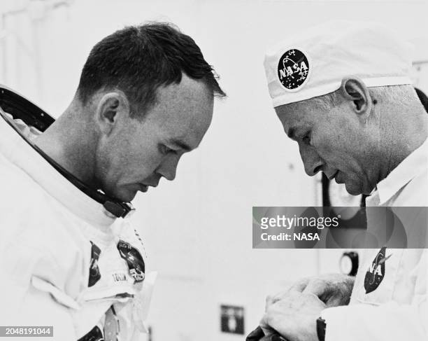 American astronaut Michael Collins, wearing his spacesuit without a helmet, during suiting operations with NASA Suit Technician Joe Schmidt, who...