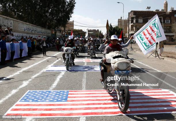 Yemen's Houthi followers driving their bikes over the American and Israeli flags during a parade staged in solidarity with Palestinians and against...