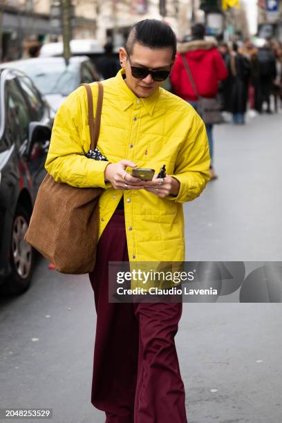 Guest wears yellow quilted jacket, burgundy pants, brown tote bag, outside Dries Van Noten, during the Womenswear Fall/Winter 2024/2025 as part of...