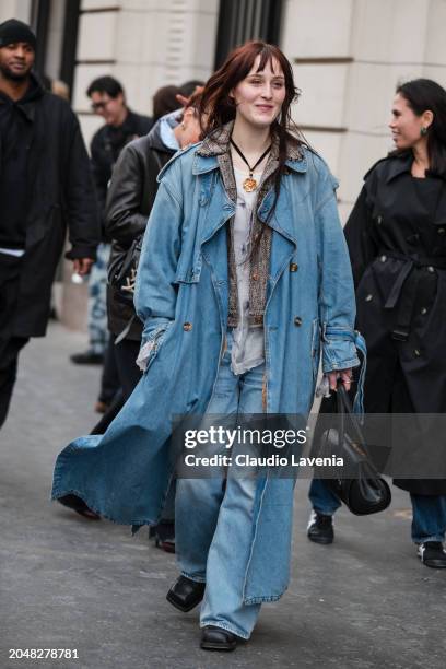 Guest wears long denim trench coat, blue jeans, black bag, black boots, outside Dries Van Noten, during the Womenswear Fall/Winter 2024/2025 as part...