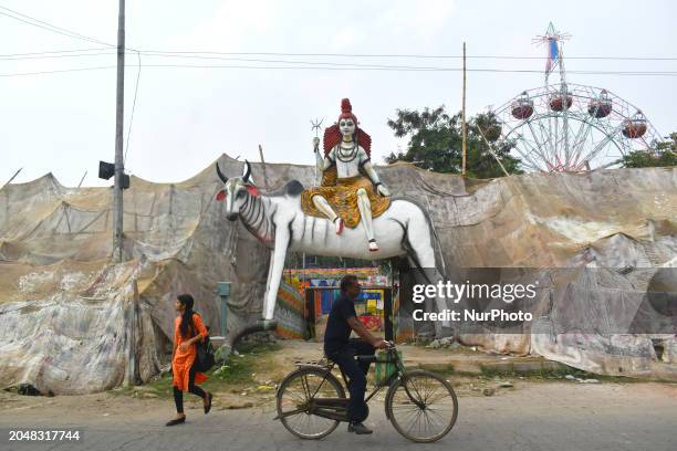 People are passing by a large idol of the Hindu lord Shiva, which has been created to mark the occasion of the Mahashivratri festival in Kolkata,...