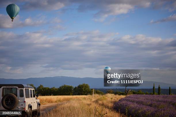 land rover 4x4 on the road next to a lavender field in provence, france (plateau de valensole), two hot air balloons floating in the air - ballon de basket stock pictures, royalty-free photos & images