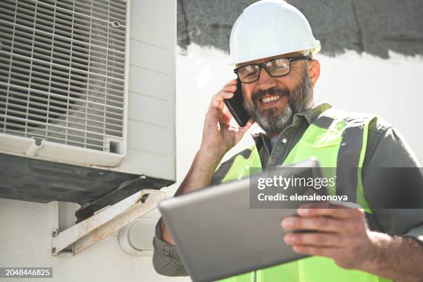 engineer repairs air conditioner - sistema de calefacción ventilazión y aire acondicionado fotografías e imágenes de stock