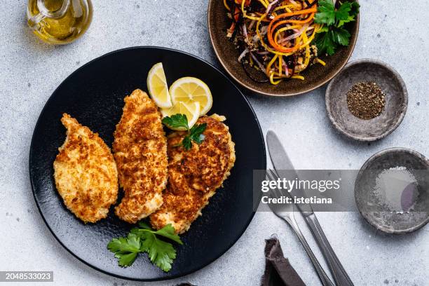 chicken schnitzel and julienne strips of purple, yellow, orange, white carrots salad - cutlet stock-fotos und bilder
