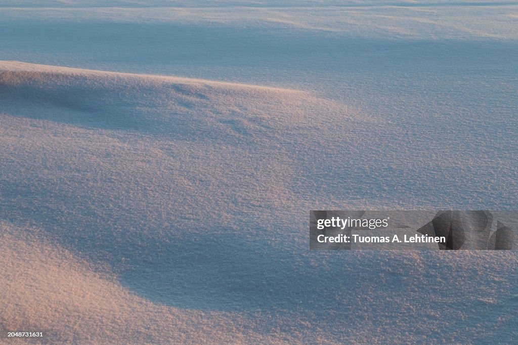 Landscape of fresh and clean snow on the ground and snowdrift at sunset.