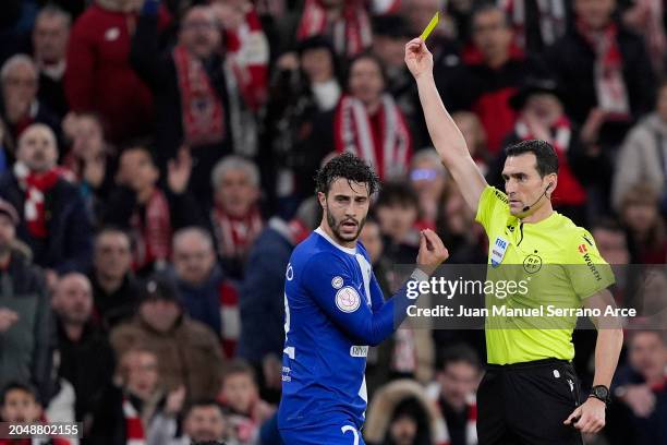 Referee Juan Martinez Munuera shows Mario Hermoso of Atletico Madrid the yellow card during the Copa del Rey Semifinal match between Athletic Club...