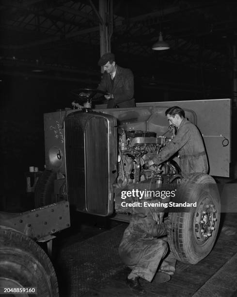 Clockwise from left, mechanics Edward Hensley, Raymond Redgewell and Frederick Carreck at work on the chassis and engine of a truck at the AEC...