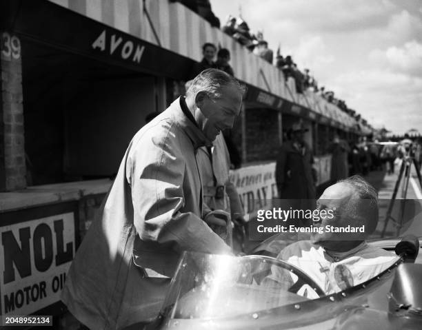 Industrialist David Brown left, with racing driver Reg Parnell seated in his race car outside a paddock ahead of the BRDC International Trophy race,...