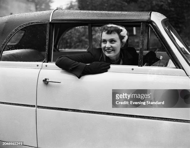 Actress Ysanne Churchman smiling from the window of the driver's seat of her car, September 26th 1955.