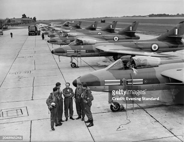 Flying Officers Ken Britton, John Collins, Robin Rose and David Eggleton of Squadron stand in a semi-circle around Squadron Leader James Casagnola,...