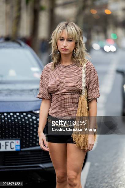 Guest wears black shorts, shirt, beige bag with fringes outside Paco Rabanne during the Womenswear Fall/Winter 2024/2025 as part of Paris Fashion...