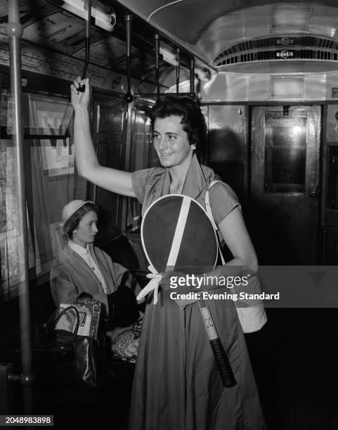 British tennis player Doreen Spiers holding her racket while commuting on a District Line tube train, London, June 1955. Spiers was competing in the...