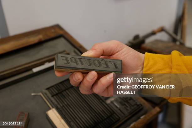 Worker holds a mould for a press printing with the logo of French sports "L'equipe" in a printing house in Nemours, central France, on February 21,...